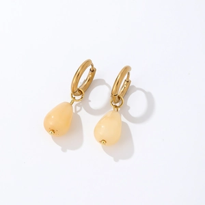 Close-up of teardrop-shaped cream stones hanging from gold-plated hoop earrings