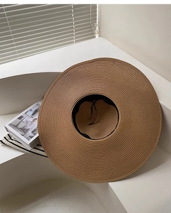 Détail d'un chapeau de soleil en paille marron à large bord avec tissage fin et cordon