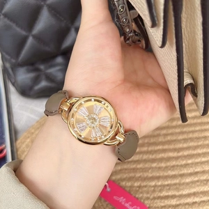 Close-up of women's gold watch with diamond floral dial and grey leather strap on wrist