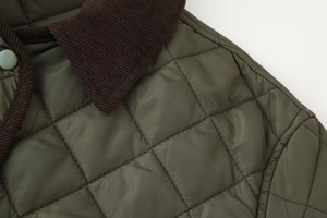 Détail de la veste matelassée à losanges avec col en velours et bouton en métal