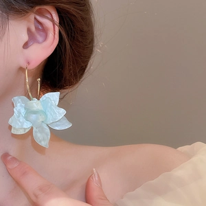 Gros plan détaillé d'une boucle d'oreille fleur en résine menthe portée pour les vacances