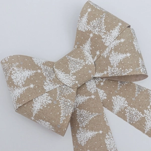 Detail of Christmas bow featuring white tree patterns and silver glitter on faux burlap