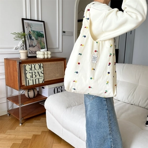 Close-up of cute floral embroidery on a white canvas tote bag with soft fabric texture