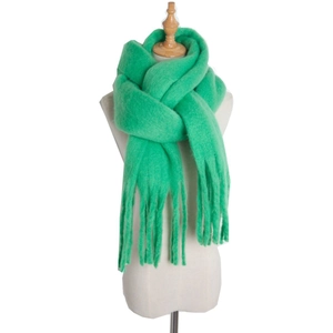 Detail of soft mohair knit scarf in bright green with thick tassels and fuzzy texture