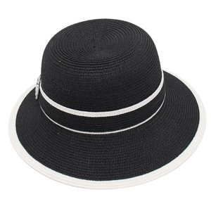 Detail of black straw sun hat featuring a white band and elegant metal side buckle