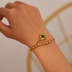 Detailed close-up of a gold beaded bracelet featuring a square emerald zircon pendant