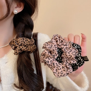 Close-up of leopard print hair scrunchies with soft fabric texture and stitched label