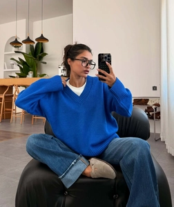 Detailed knit texture of Klein blue V-neck oversized sweater with loose draped sleeves