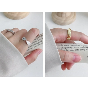 Detail of Mobius twisted silver and gold rings worn on fingers in a minimalist setting