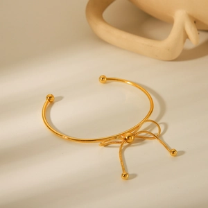Detail of an 18K gold-plated stainless steel bow open bangle with spherical ends