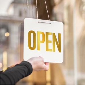 Close-up of elegant gold OPEN sign held in front of shop door for store decoration