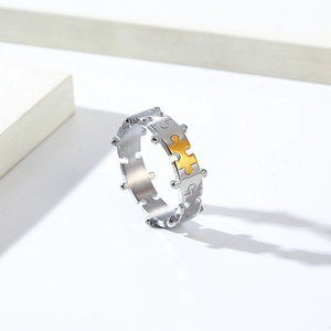 Macro detail of silver puzzle ring with a gold accent plate on a white geometric background