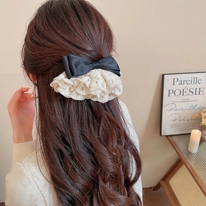 Pince à cheveux élégante avec nœud en satin noir et dentelle beige sur cheveux bouclés