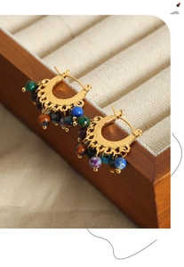 Gros plan de boucles d'oreilles créoles dorées avec perles d'agate colorées style ethnique