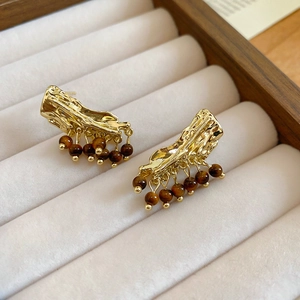 Vue détaillée des boucles d'oreilles dorées texturées et perles brunes en coffret