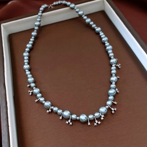 Detail of blue-grey pearl necklace with sparkling snowflake pendants on dark tray