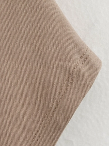 Macro shot of khaki knit fabric texture and high-quality stitching detail on the garment