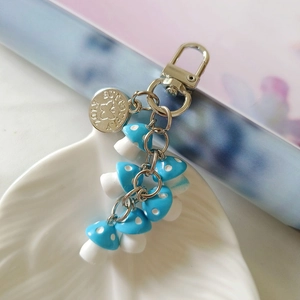 Detailed close-up of blue mushroom charm keychain on white ceramic plate