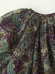 Close-up of metallic paisley chiffon fabric with elegant pleated neckline details