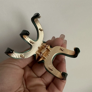Close-up of golden alloy hair claw clip with dark acetate texture and fine metal details