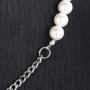 Macro detail of white pearls connected to a silver Cuban chain with a secure lobster clasp