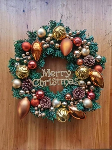 Detailed view of Christmas wreath with gold pinecones and Merry Christmas logo