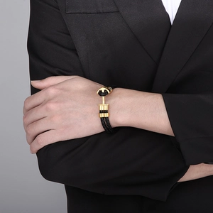 Close-up of men's black braided leather anchor bracelet with gold buckle on a male wrist
