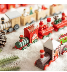 Macro detail of wooden Christmas train toy set nestled in snow with pine cones