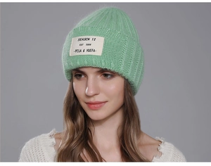 Detail of light green rabbit fur beanie showing ribbed texture and SEASON 12 patch