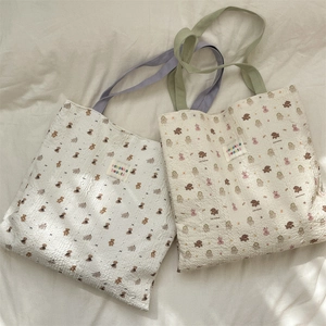 Close-up of seersucker tote bag with embossed bear pattern and colorful animal prints