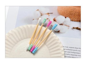 Macro shot of colorful spiral-tipped bamboo cotton swabs with a natural cotton background