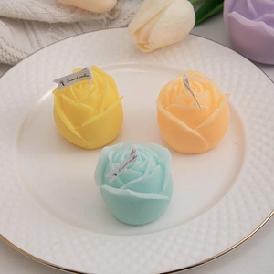 Three colorful rose shaped scented candles in a white ceramic tray with floral decor