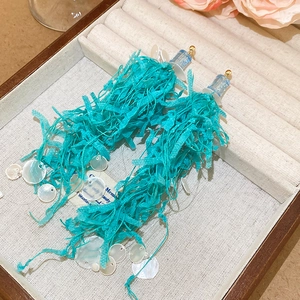 Detail of blue lace tassels earrings with white shell accents on velvet jewelry tray