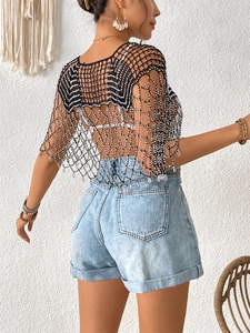 Détail du poncho au crochet noir et blanc avec perles et glands bohèmes pour la plage