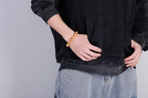 Close-up of chunky gold-tone link chain bracelet worn on wrist for a punk style
