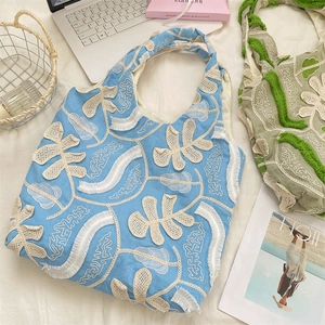 Détail de la broderie florale et des franges d'un sac sous les bras bleu vintage