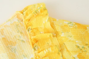 Detail of yellow floral fabric with pleated texture and delicate ruffle accents