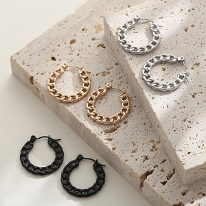Detail of three pairs of chain-style hoop earrings in gold, silver, and black finish