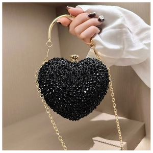Close-up of heart-shaped black evening bag with rhinestones and gold snake-bone handle