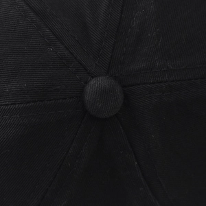 Close-up of the stitched top button and twill fabric texture on a washed black baseball cap