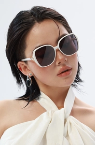 Gros plan de lunettes de soleil carrées blanches polarisées avec détails dorés sur modèle