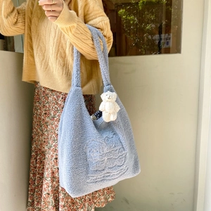 Detailed close-up of light blue plush tote bag with bear embroidery and soft fleece texture