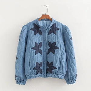 Women's light blue quilted jacket with dark blue floral patches and puff sleeves