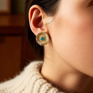 Macro shot of gold vintage flower earring with a green gemstone on a female model