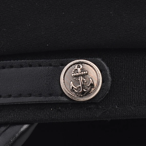 Détail de casquette militaire noire avec bordure en cuir et bouton à motif d'ancre