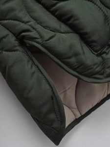Detailed view of quilted jacket stitching with dark green fabric and taupe lining contrast