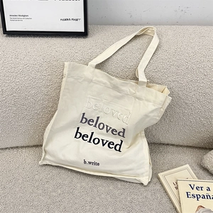 Detail of beloved letter embroidery on off-white canvas tote bag with thick texture