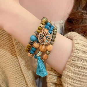 Detail of bohemian multilayered sandalwood beaded bracelet with tree of life charm and tassel