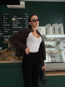Detailaufnahme der braunen Strickjacke mit Reißverschluss und weißem Body im Café-Stil
