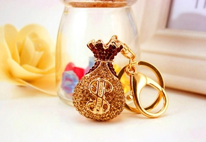 Macro shot of gold money bag keychain with crystal embellishments and dollar sign symbol